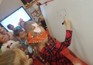 dziewczynka rysuje misia z zamkniętymi oczyma wg instrukcji dzieci